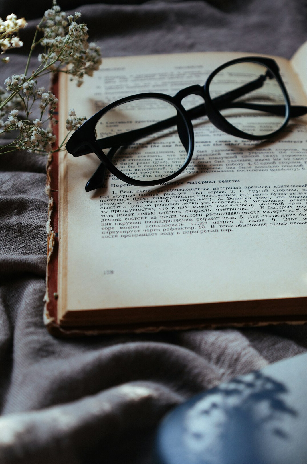 Open vintage book with handwritten notes and reading glasses on a wooden table