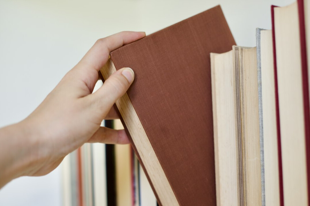 Tall library shelves full of old books with a rolling ladder