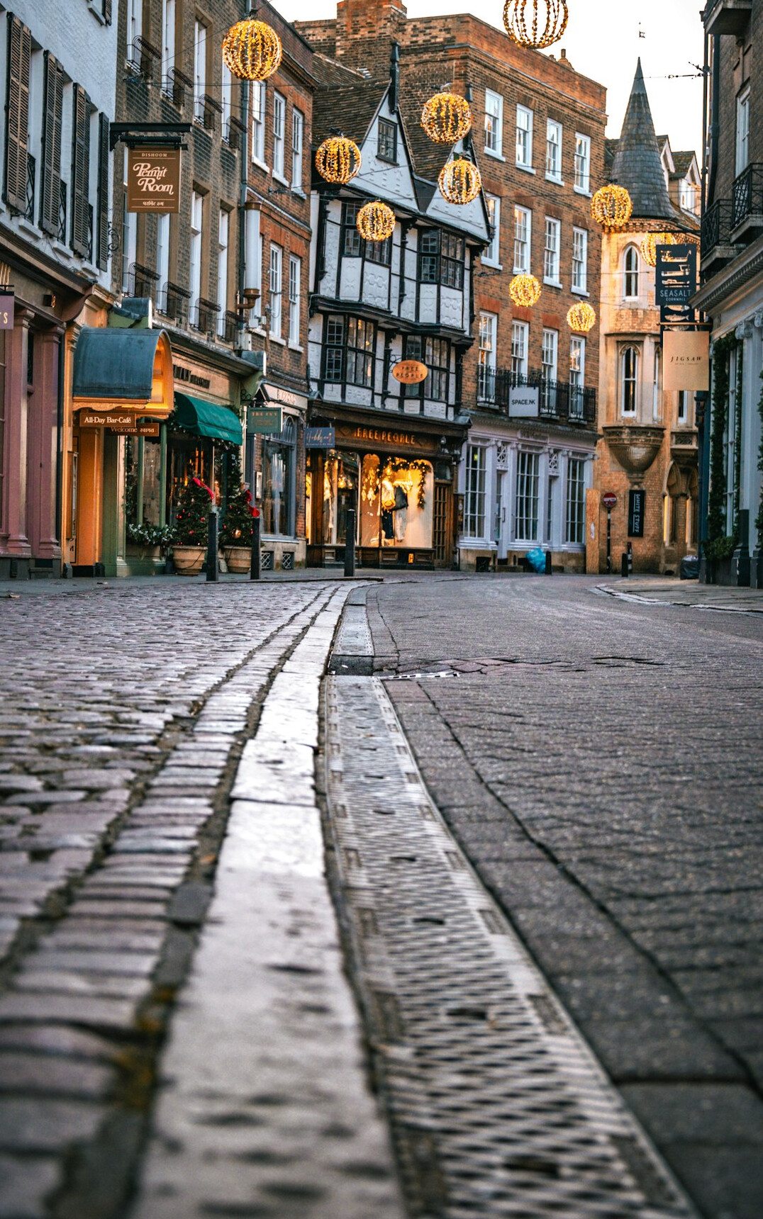 Rainy cobblestone street in an old city at dusk with historic buildings