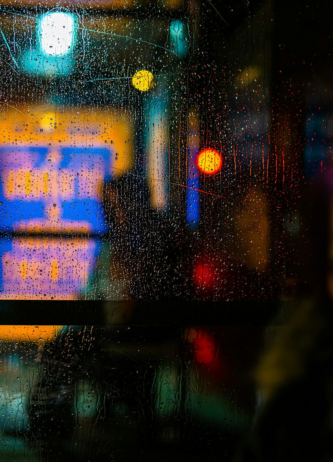 Rainy window with blurred city lights at night